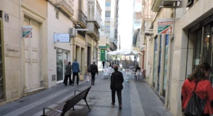 Calle Castelar en Almería, un estrecho pasaje peatonal lleno de actividad comercial con tiendas locales.
