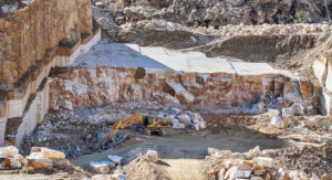 Excavadora trabajando en una cantera de mármol a cielo abierto con grandes bloques de piedra en Macael, Almería.